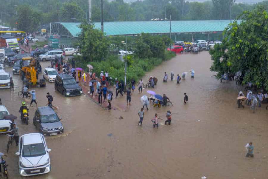 Commuters make their way through a waterlogged road amid rainfall, in Gurugram, Monday, Sept. 1, 2025. 