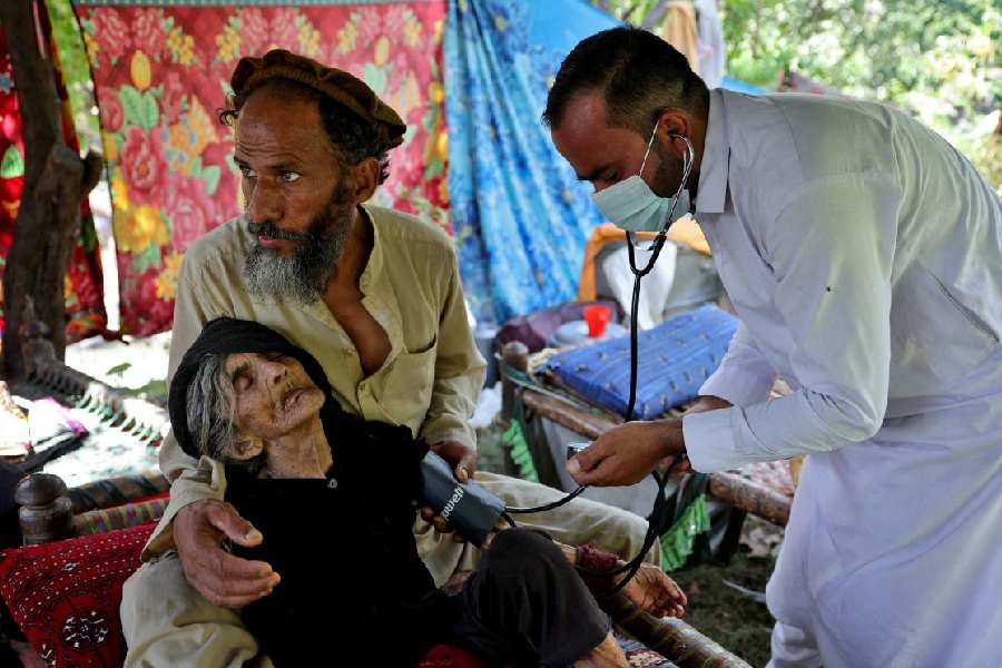 A doctor tends to Rad Bibi, an injured Afghan woman who claims to be 110-years-old, outside her damaged house (Reuters)