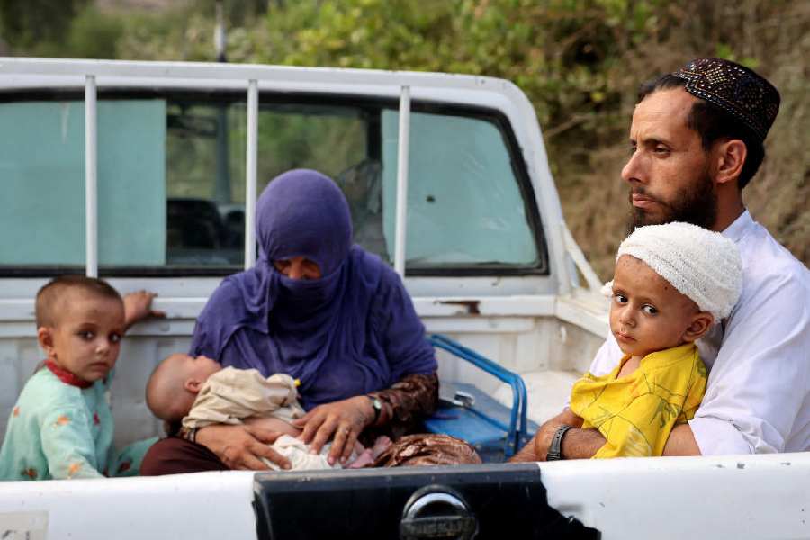 An injured child sits in his father's lap as they travel in a vehicle(Reuters)