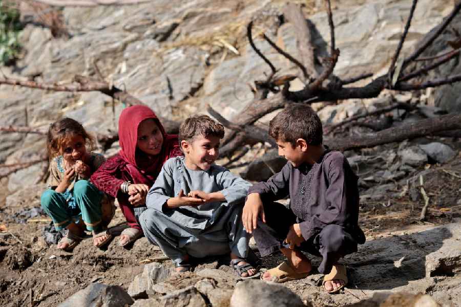 Afghan children play outside their damaged houses (Reuters)
