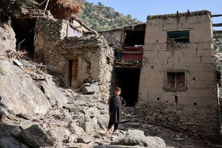 A boy stands in front of houses damaged by the deadly earthquake (Reuters)