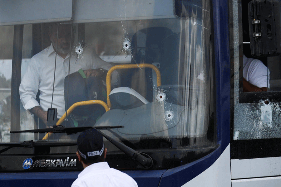 People inspect a bus with bullet holes in the windshield at the scene where a suspected shooting attack took place at the outskirts of Jerusalem, September 8, 2025.