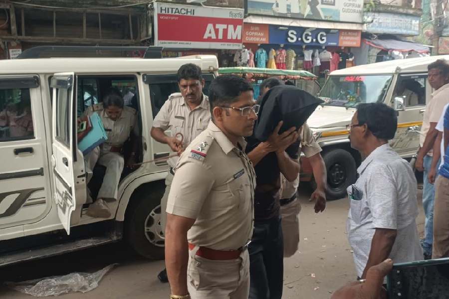 The police take the accused teacher, Manoj Kumar Pal (masked), to the court in Rampurhat on Wednesday.