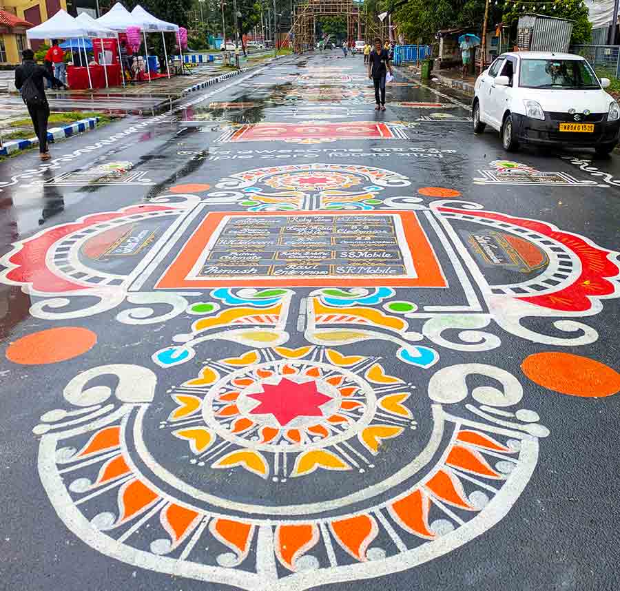 The massive alpana glistened on the city’s street on a rainy afternoon as passers-by stopped to admire it