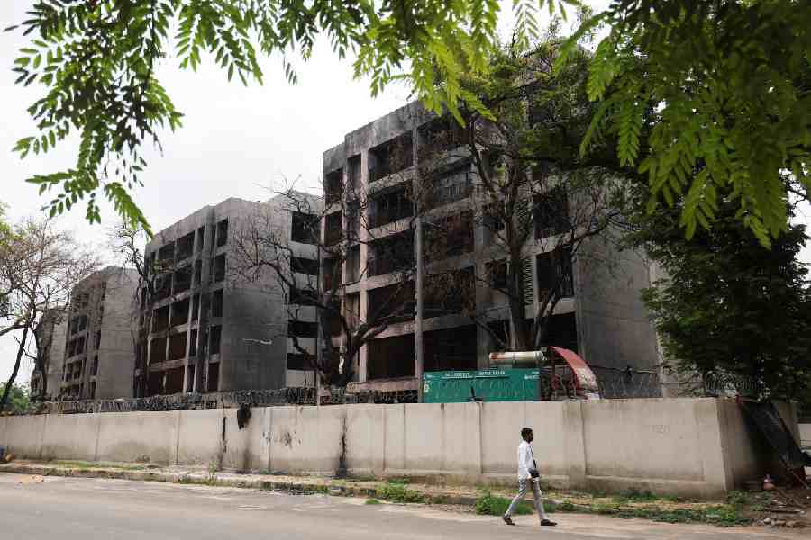 A plain clothed policeman passes by damaged buildings, where an Air India Boeing 787-8 Dreamliner plane crashed during takeoff from a nearby airport, in Ahmedabad