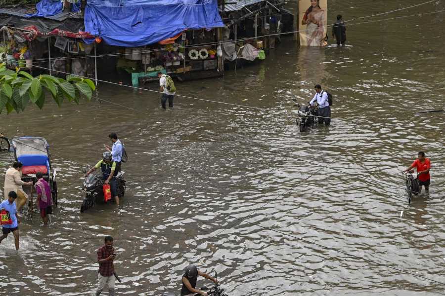 Commuters make their way through a waterlogged road following rain, in Kolkata, Tuesday, Sept. 23, 2025.