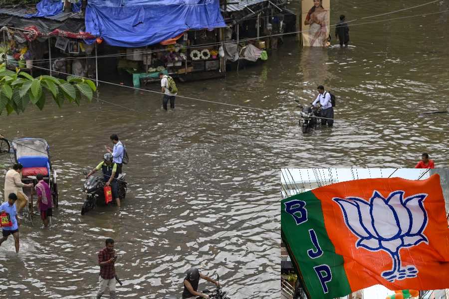 Commuters make their way through a waterlogged road following rain, in Kolkata, Tuesday, Sept. 23, 2025.