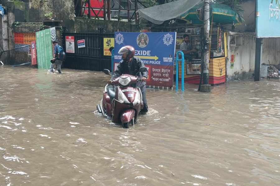A scooterist tries to navigate the road amid knee-deep water in Calcutta on Tuesday.