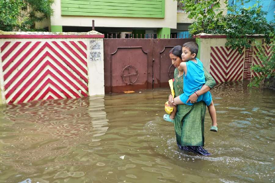 A mother carries her child while walking through knee deep water in Patuli on Wednesday