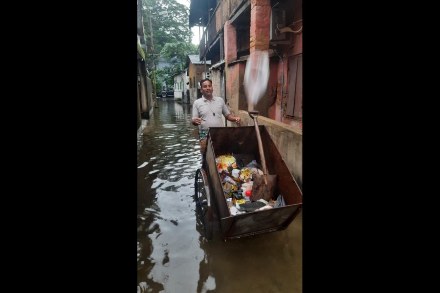 Civic body staffer Taleswar Das walks on slush on a Paikpara bylane, Calcutta, with his cart to collect trash from residents on Tuesday morning