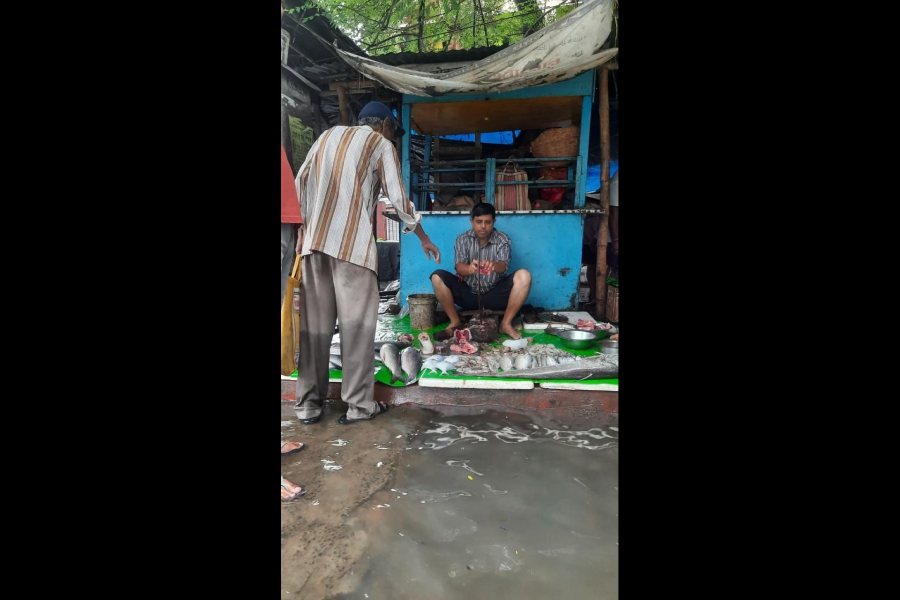 Fishseller Prabir Ghosh caters to a customer at the waterlogged Ashu Babur Bazaar in north Calcutta on Tuesday morning