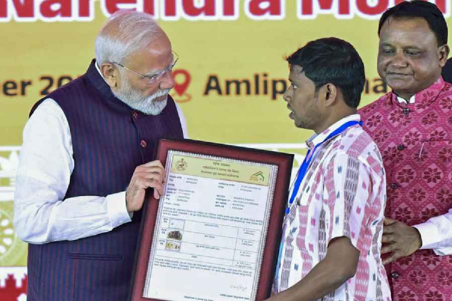 Prime Minister Narendra Modi hands over a sanction order to a beneficiary of the Antyodaya Gruha Yojana as chief minister Mohan Charan Majhi looks on at the rally in Jharsuguda, Odisha, on Saturday.