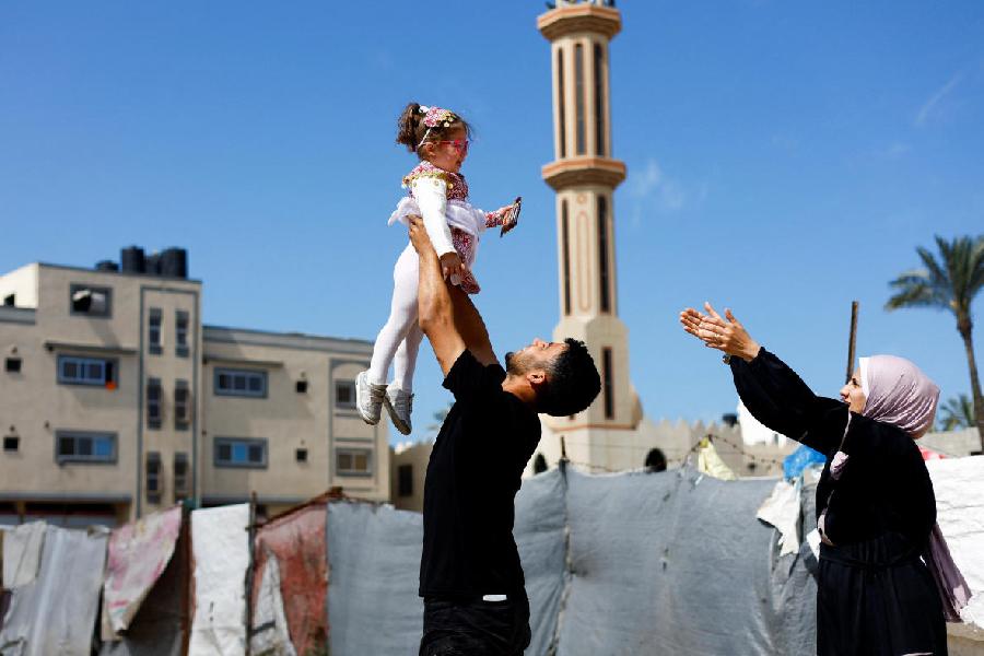 Maternal uncle of Bissan, who was evacuated as a premature baby during the two-year Israeli offensive for treatment in Egypt, plays with her after she returned to Gaza as her Palestinian mother Sundus al-Kurd reaches her arms out, in Deir al-Balah in the central Gaza Strip, March 31, 2026.