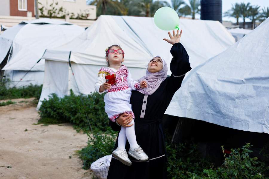 Palestinian mother Sundus al-Kurd carries her daughter Bissan, who was evacuated as a premature baby during the two-year Israeli offensive for treatment in Egypt, after her return to Gaza, outside their tent in a camp in Deir al-Balah in the central Gaza Strip, March 31, 2026.