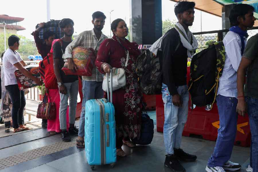 Migrant labourers stand in a queue with their belongings at a railway station in New Delhi on Thursday.