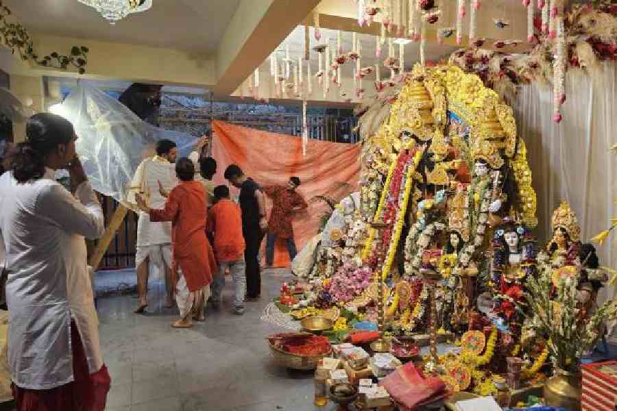 Residents put up plastic sheets to guard the Basanti idol against a hailstorm and shower in a DB Block house in New Town. (Sudeshna Banerjee)