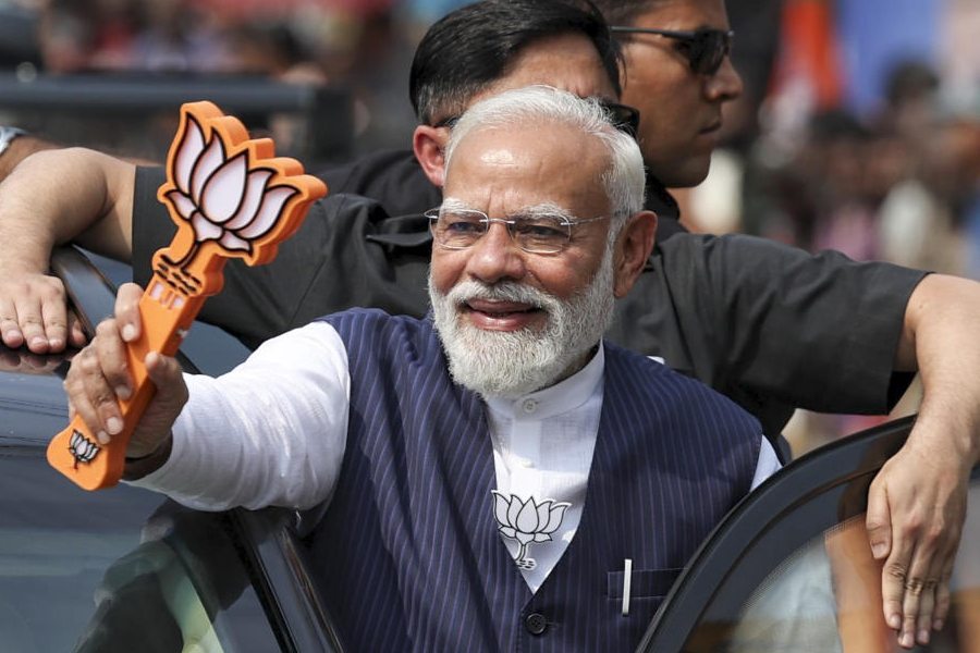 In this image posted on April 4, 2026, Prime Minister Narendra Modi holds a party symbol during a roadshow ahead of the Kerala Assembly elections, in Thiruvalla, Kerala.
