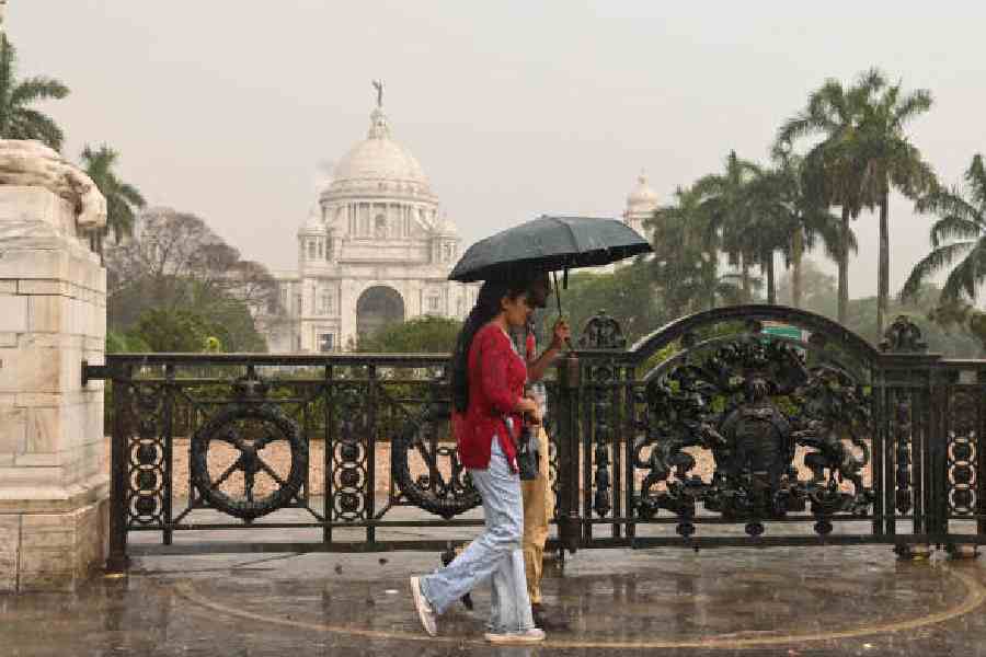 Visitors to the Victoria Memorial walk amid rain on Sunday afternoon.