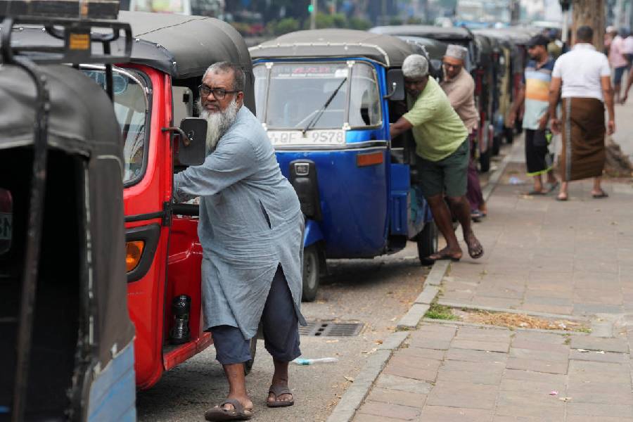 Drivers push their autorickshaws as they wait in a queue to refuel outside a fuel station, after the government declared a weekly Wednesday holiday for public officials to conserve fuel amid concerns over fuel supplies during the US-Israel conflict with Iran, in Colombo, Sri Lanka, March 18, 2026.