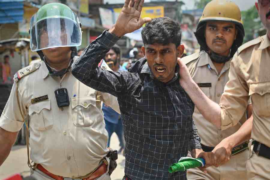 A man being held by the collar by Bengal police officials.