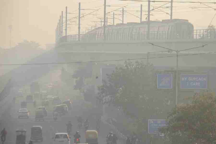 A Delhi Metro train passes by while vehicles ply on a road amid smog, in Gurugram, Haryana, Thursday, Nov. 6, 2025.