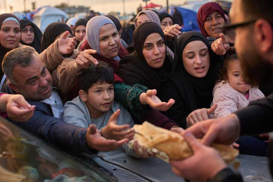 Displaced families extend their hands while waiting for donated food beside the tents they use as shelters after fleeing Israeli bombardment in southern Lebanon, in Beirut, Lebanon, Thursday, April 9, 2026.