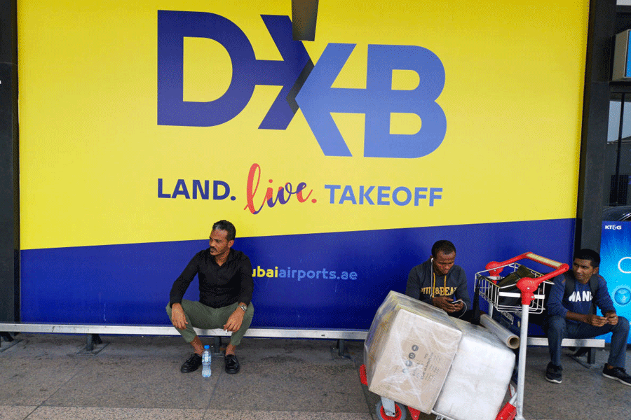 FILE PHOTO: Passengers sit next to a new logo of Dubai Airport, at the departure hall of terminal one, Dubai