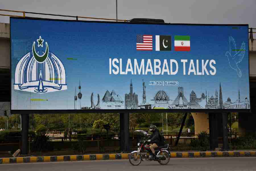 A man rides his motorbike past a billboard installed alongside a road as Pakistan prepares to host the U.S. and Iran for peace talks, at a barber shop in Islamabad, Pakistan, April 10, 2026.