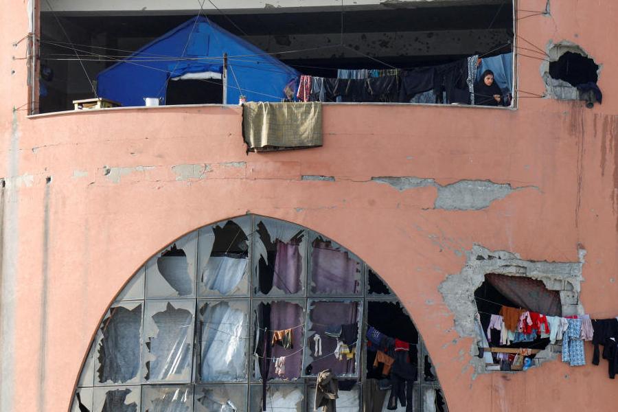 A displaced Palestinian woman stands on a balcony inside a building damaged during the war at Al-Aqsa University, now used as a shelter, in Khan Younis, southern Gaza Strip, April 5, 2026.