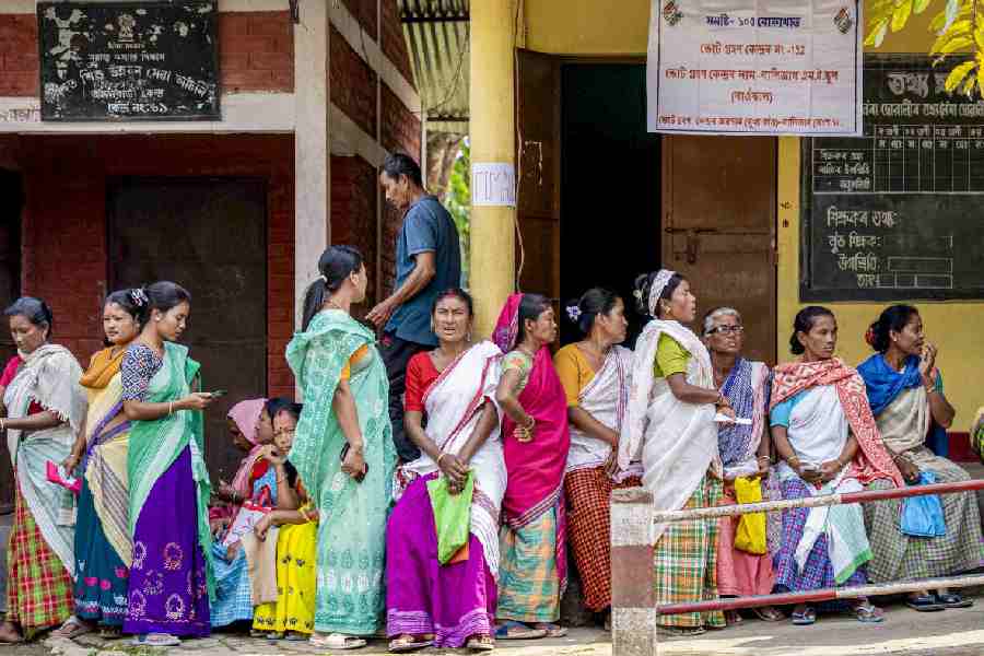 People on Thursday wait outside a polling station in Assam’s Golaghat district.
