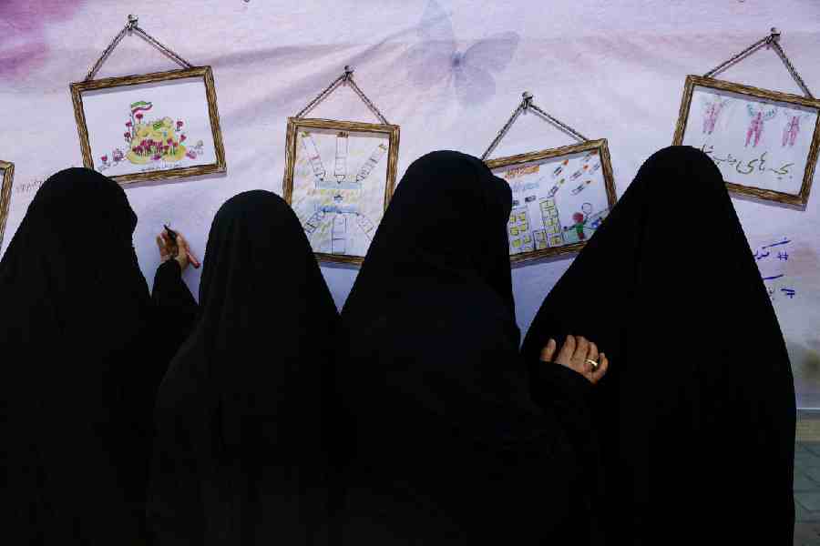 Four burkha-clad women draw on a canvas