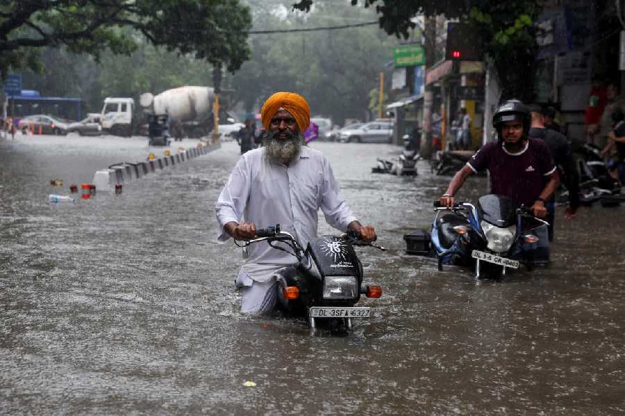 A man on his motorbike wades through a flooded street after heavy rains in New Delhi, India, July 8, 2023.