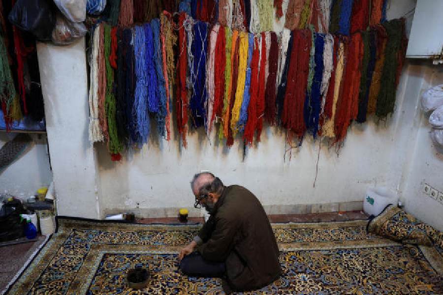 A craftsman repairs carpets inside a workshop at Tehran’s Grand Bazaar on Monday.