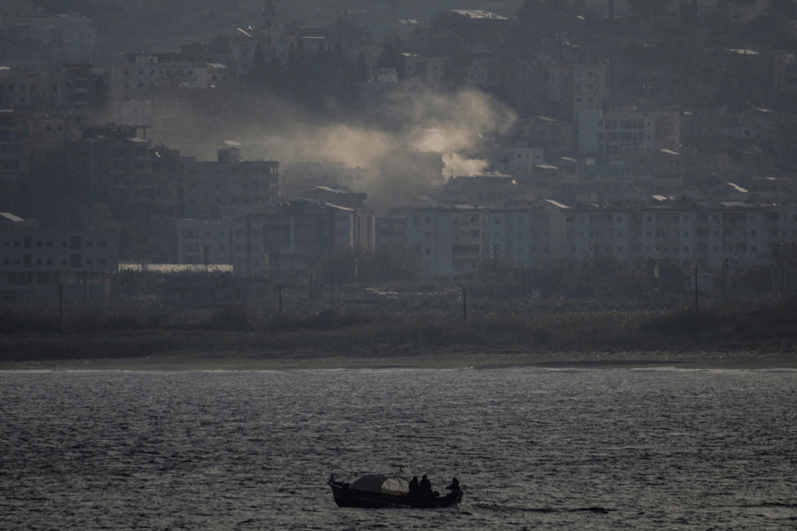 Fishermen sail their boat as smoke from an Israeli airstrike rises in Abbassiye area in Tyre, Lebanon, April 14, 2026.