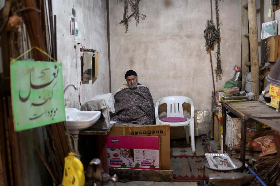 A man sits inside a small shoe repair workshop at the Grand Bazaar in Isfahan, Iran, March 24, 2026. 