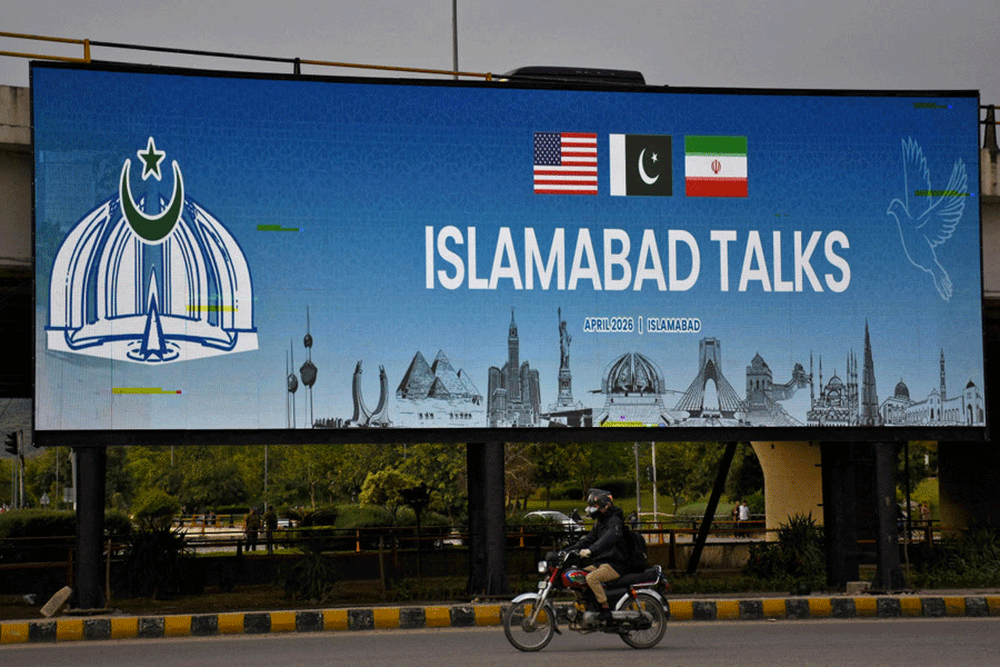 FILE PHOTO: A man rides his motorbike past a billboard installed alongside a road as Pakistan prepares to host the U.S. and Iran for peace talks, in Islamabad, Pakistan, April 10, 2026.