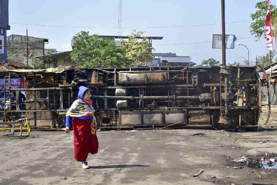 A woman walks past chassis of a bus amid tense situation, with curfew, internet suspension and heavy police deployment, in the aftermath of violence that broke out following a bomb attack in Bishnupur on Tuesday, leaving two children dead, in Imphal, Manipur, Wednesday, April 8, 2026.