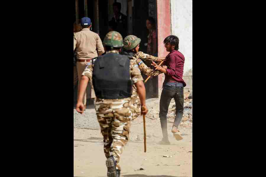 A policeman hits a man in a migrant neighbourhood in Noida on Tuesday.
