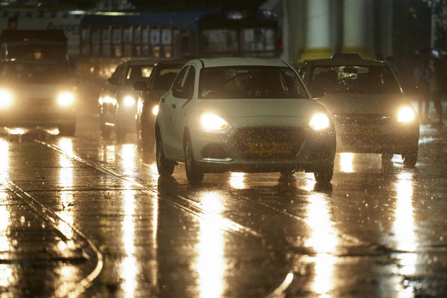 Vehicles ply on a rain-soaked road during rainfall, in Kolkata.