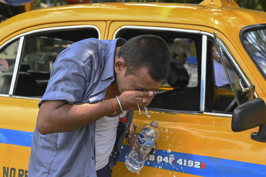 A driver splashes water on his face to get relief from the scorching heat on a hot summer day, in Kolkata