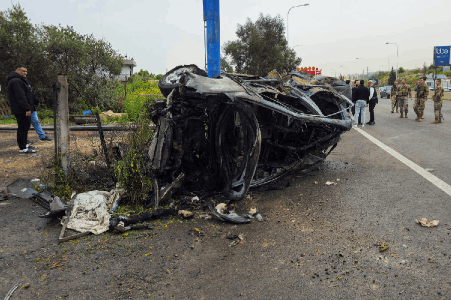 People and Lebanese army soldiers gather around a vehicle hit in an Israeli strike in Saadiyat, Lebanon, April 15, 2026.