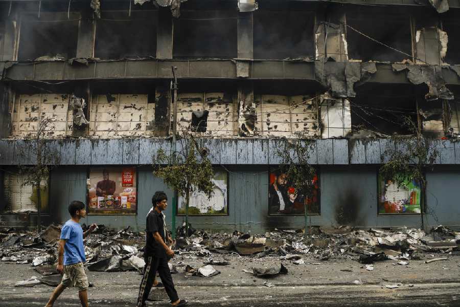 People walk past the charred remains of a supermarket, a day after it was set ablaze by agitators during anti-government protests, in Kathmandu, Nepal.