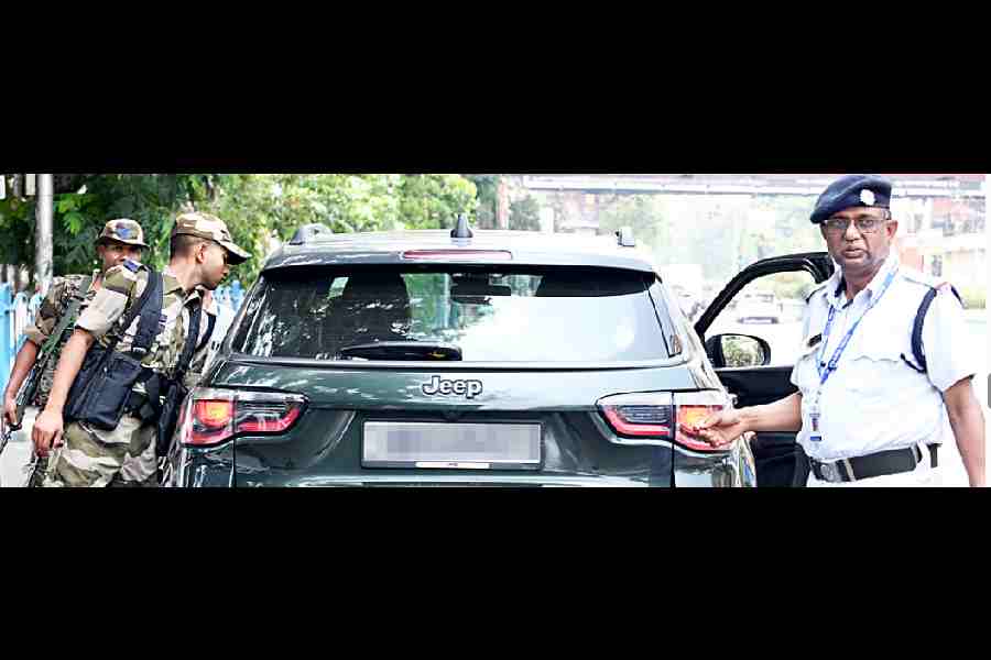 Central force jawans and a police officer check a car near the Exide crossing on Wednesday.