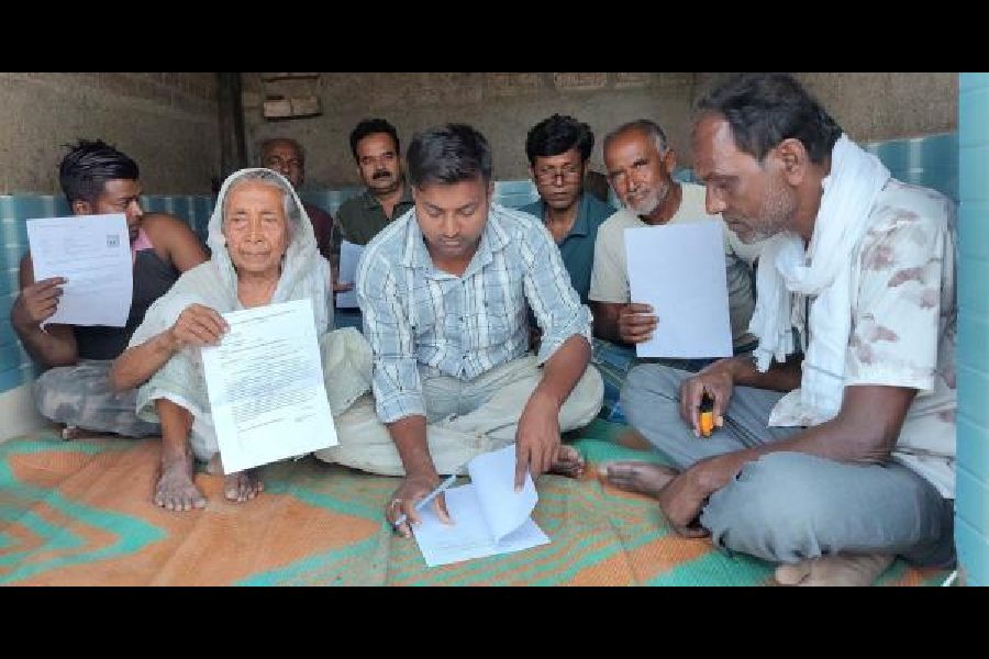 A youth helps deleted voters in Nadia’s Chandanpur village write their petition forms.