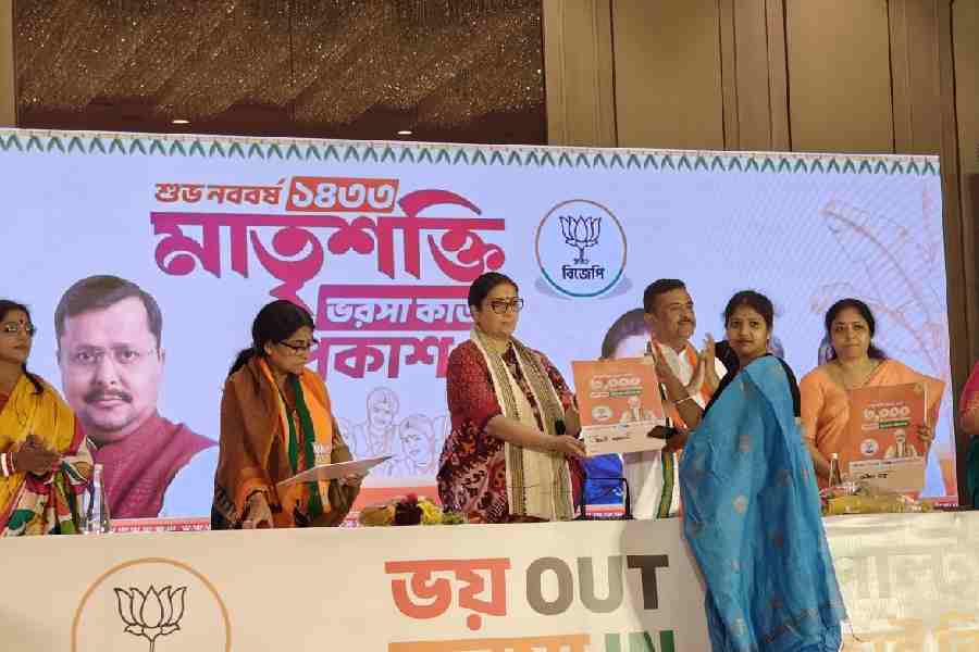 Smriti Irani hands over a Matrishakti Bharosa Card to a woman at a private hotel in New Town on Wednesday