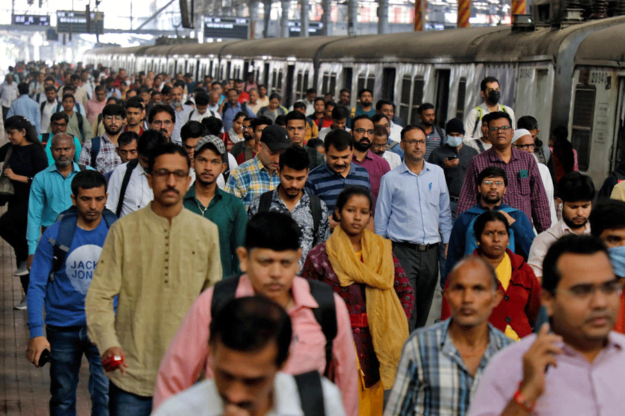Commuters walk on a platform after disembarking from a suburban train, in Mumbai