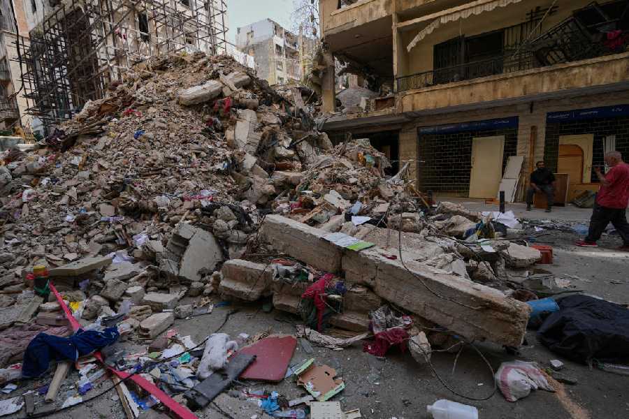 Residents stand next to the rubble of a destroyed building that was hit a week ago in an Israeli airstrike in central Beirut, Lebanon, Thursday, April 16, 2026.