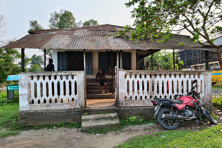 A worker sits in front of his ancestral house in a tea estate.