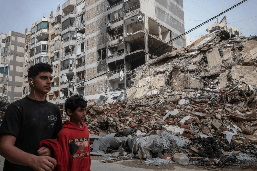People walk past a destroyed building, after a 10-day ceasefire between Lebanon and Israel went into effect, at the southern suburbs of Beirut, Lebanon, April 18, 2026.