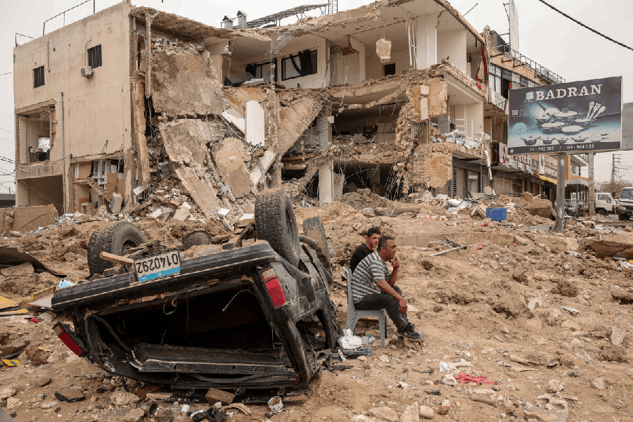 People sit at the site of an Israeli strike carried out just before a 10-day ceasefire between Lebanon and Israel went into effect, in the Abbassye area of Tyre, Lebanon, April 18, 2026.